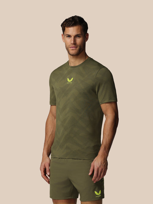Man wearing a green athletic outfit with a logo on a beige background