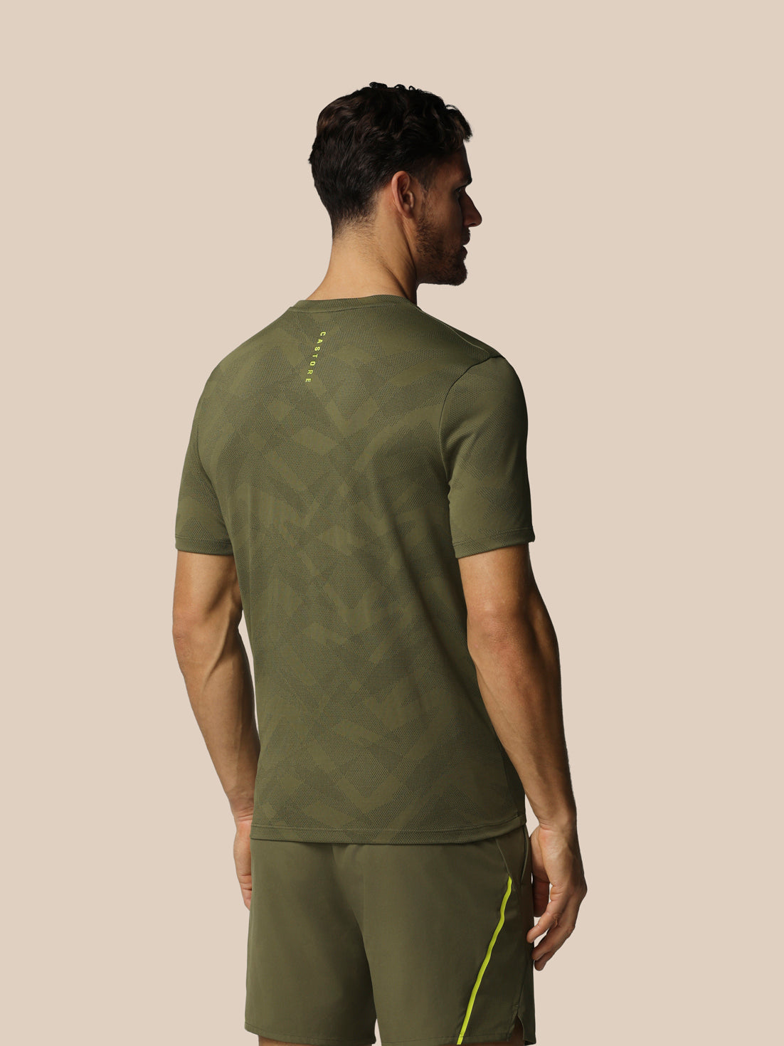 Man wearing a green athletic outfit on a beige background