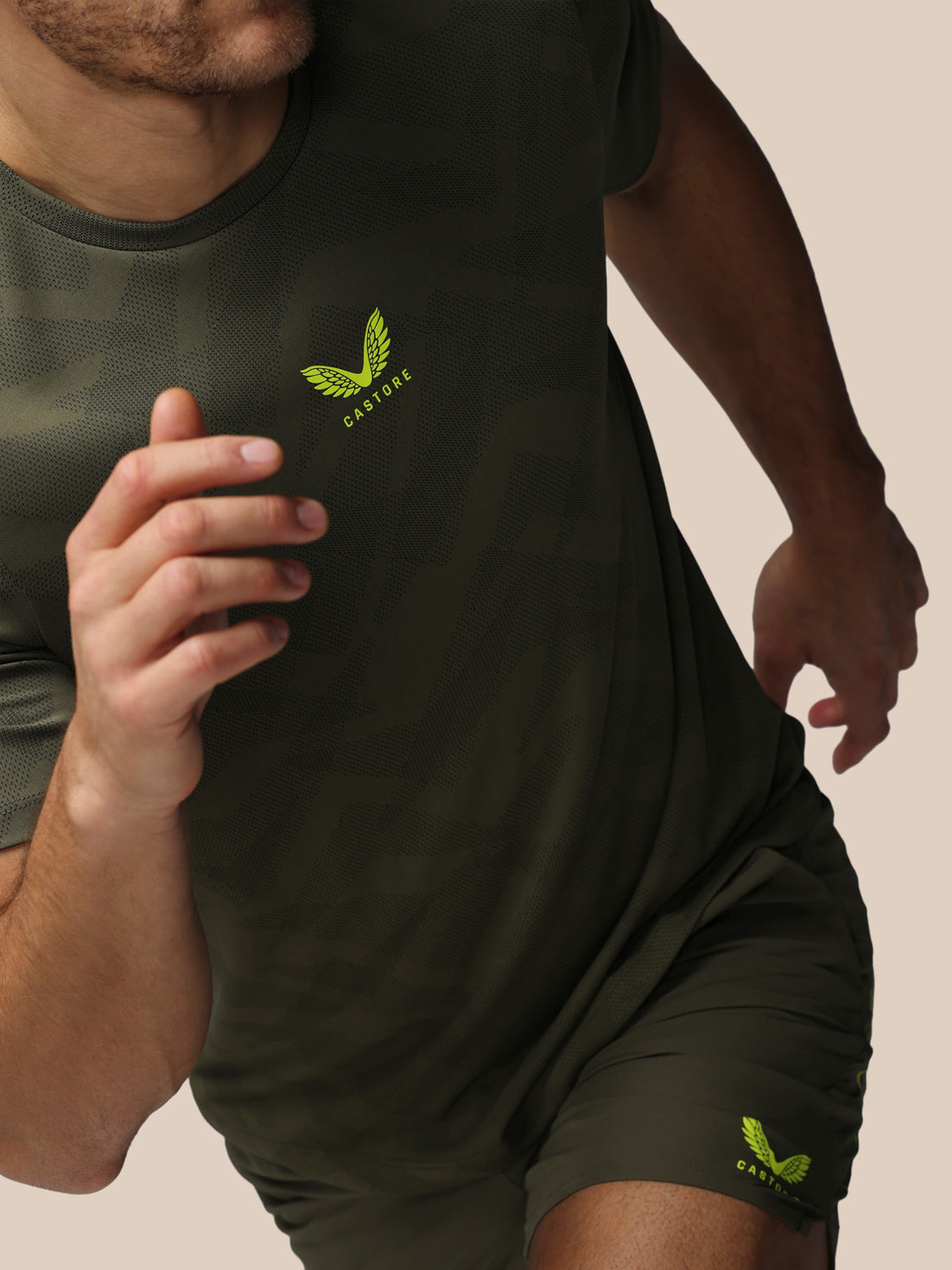 Person wearing a dark green t-shirt and shorts with a logo on a beige background