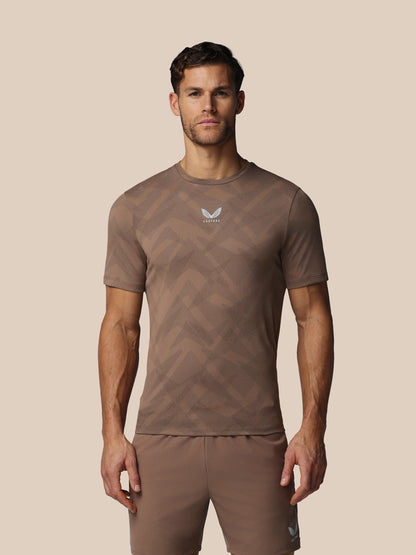 Man wearing a brown athletic outfit with a logo on a beige background