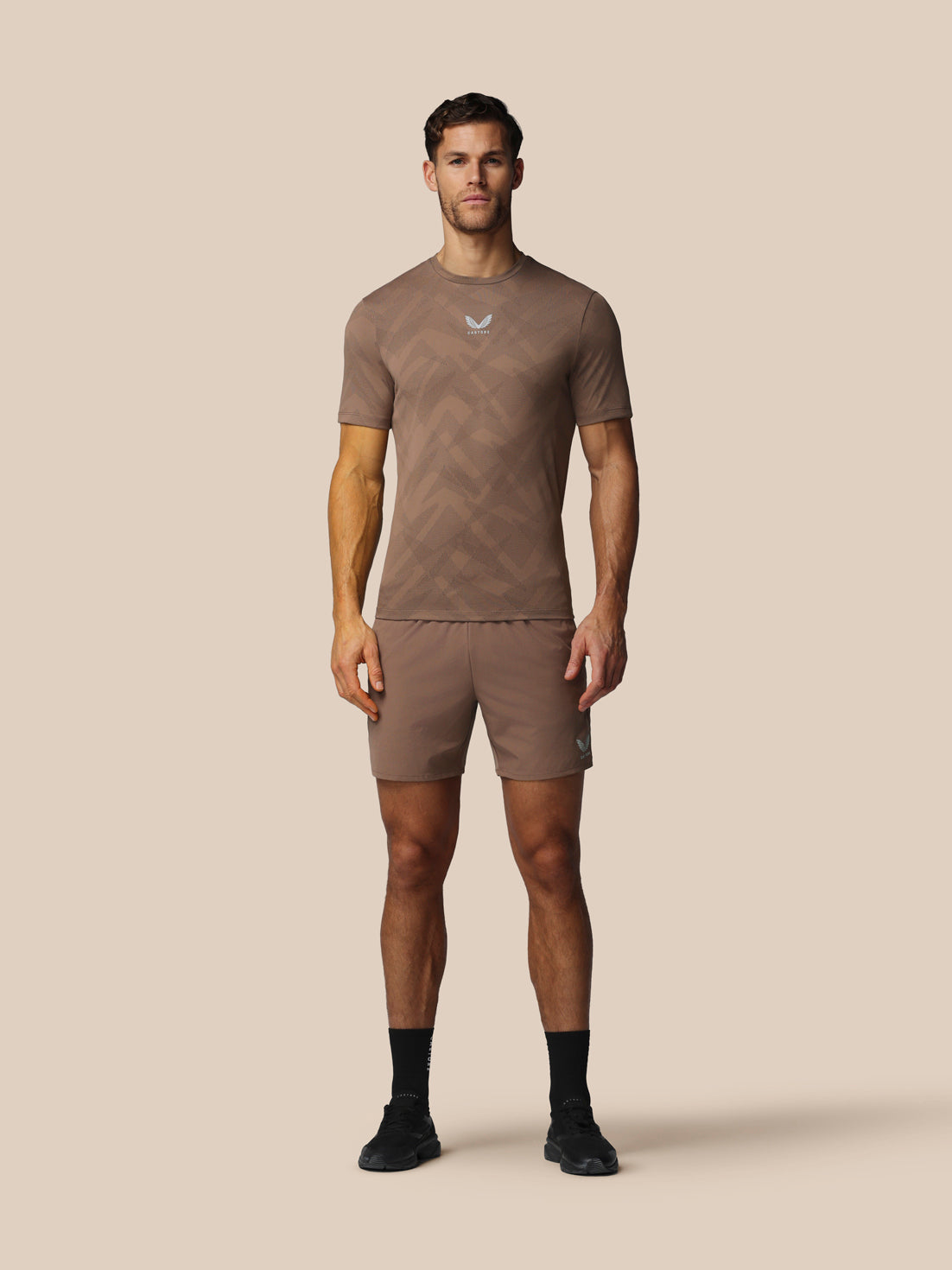 Man wearing a brown athletic outfit on a beige background