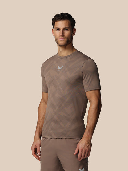 Man wearing a brown athletic outfit with a logo on a beige background