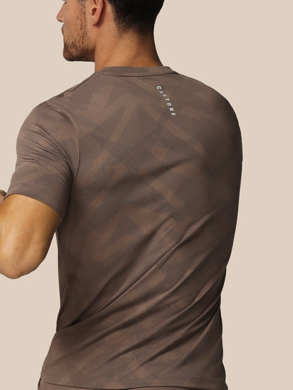 Man wearing a brown t-shirt with a logo on the back against a beige background