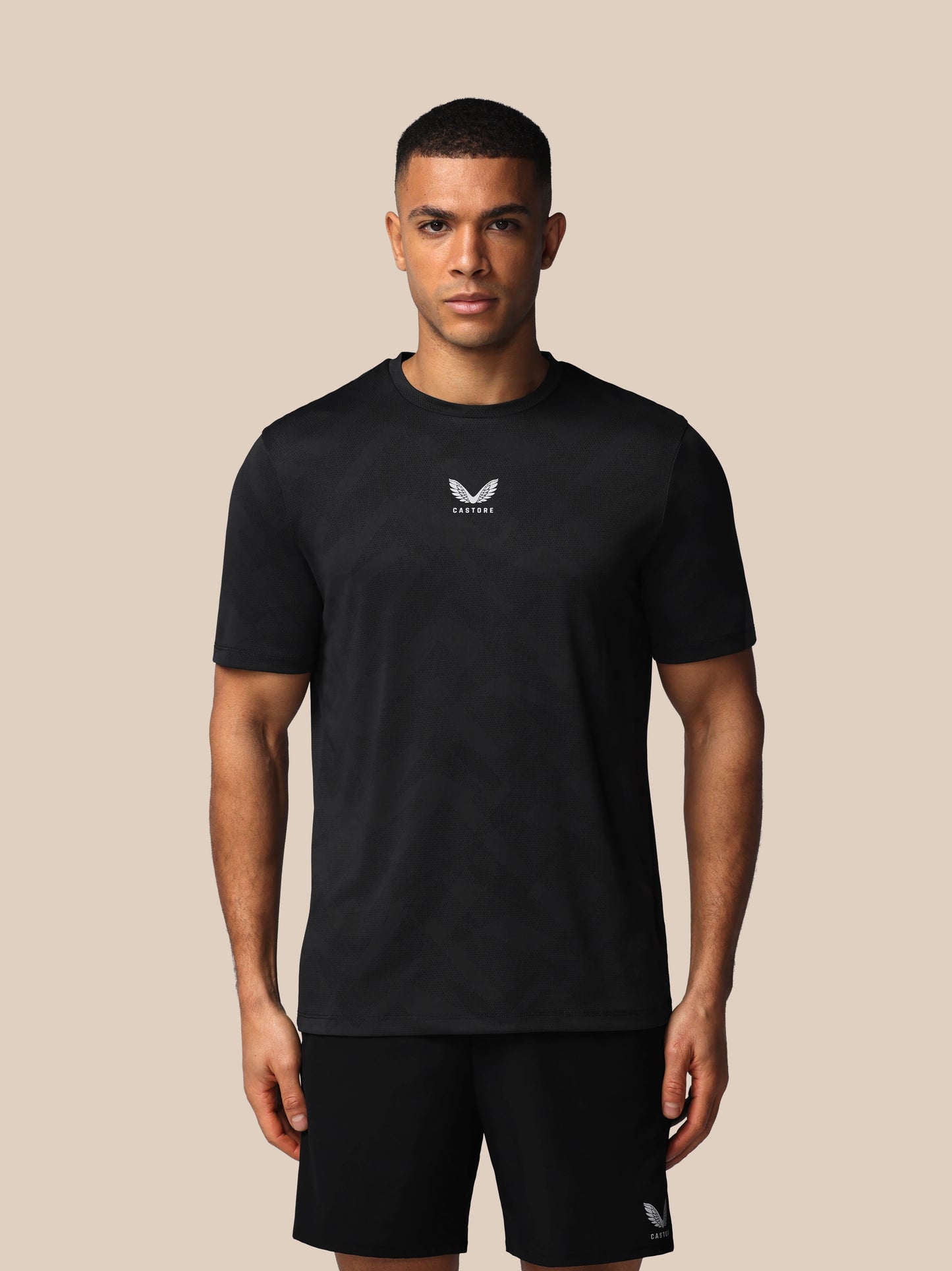 Man wearing a black t-shirt with a logo on a beige background
