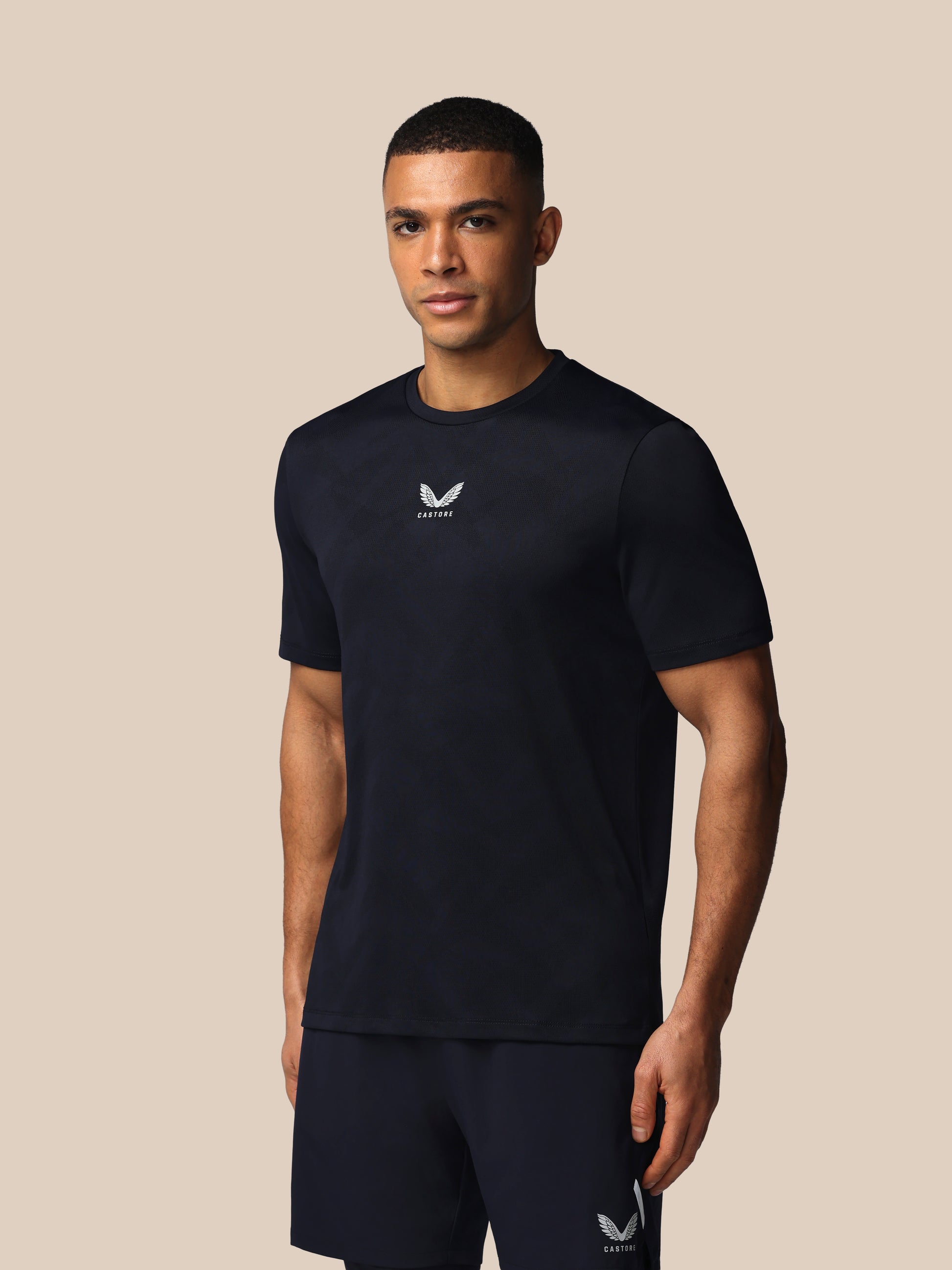 Man wearing a black t-shirt with a logo on a beige background
