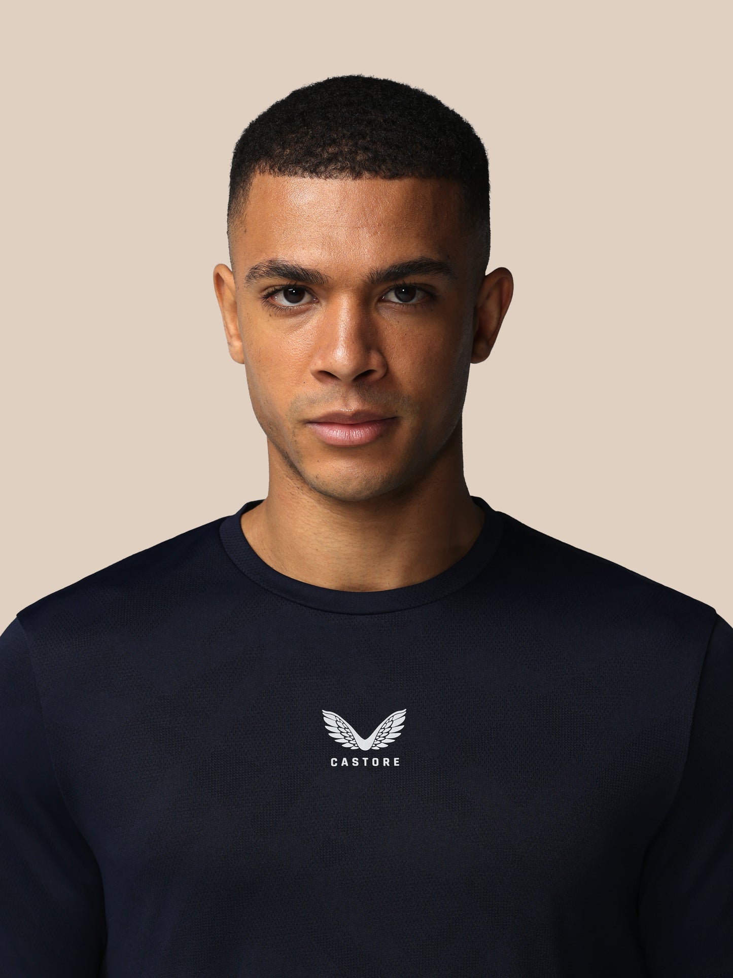 Man wearing a black sweatshirt with a logo on a beige background