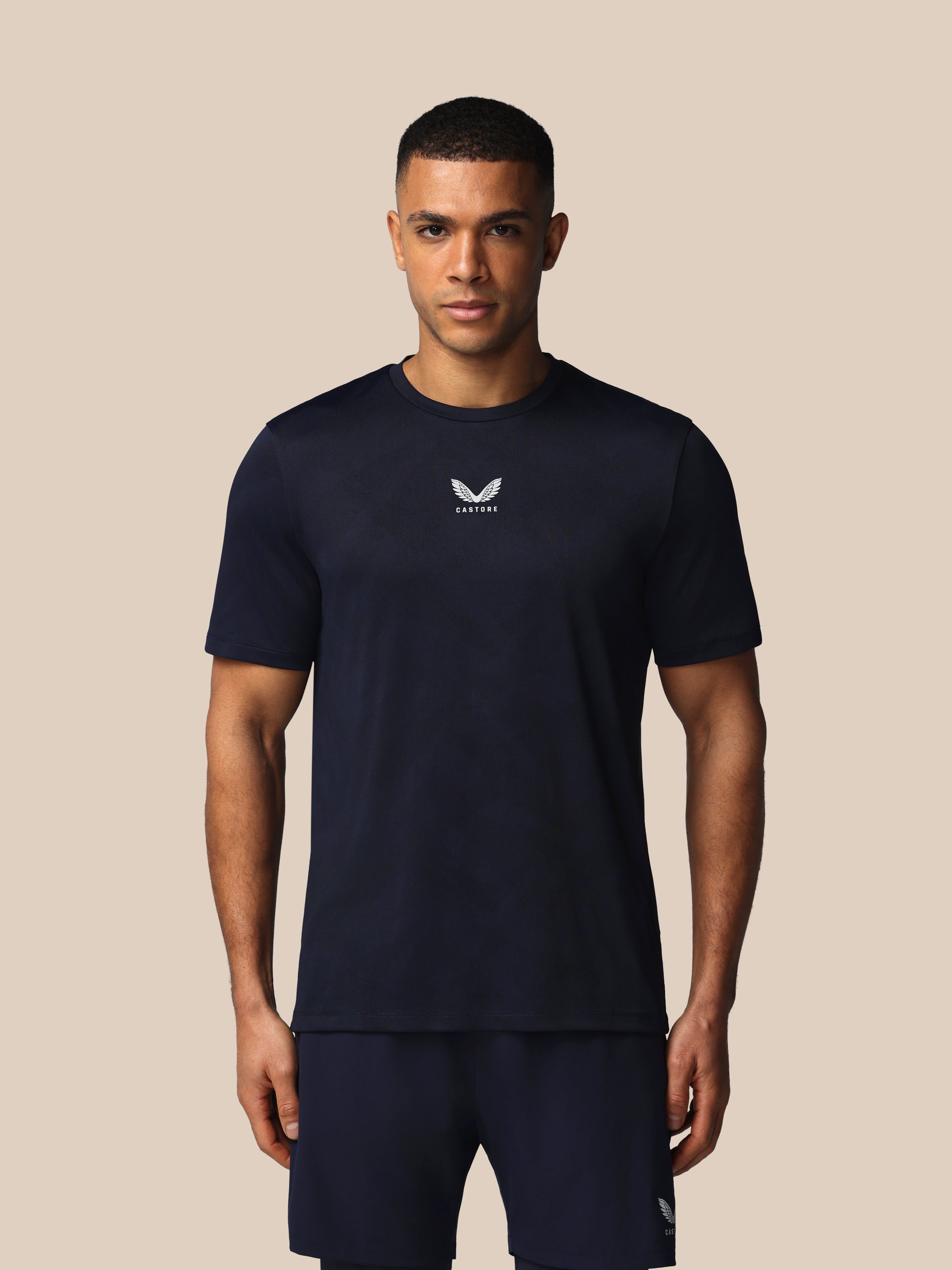 Man wearing a black t-shirt with a logo on a beige background