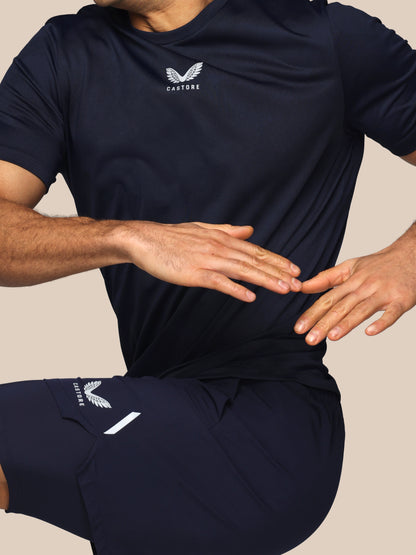 Person wearing navy athletic outfit with brand logo on a neutral background