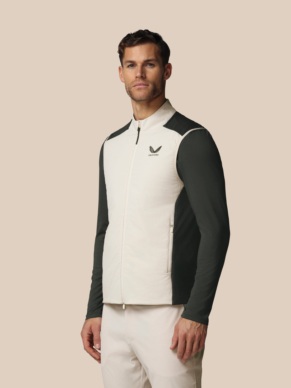 Man wearing a white and black jacket with a logo on a beige background