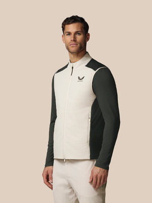 Man wearing a white and black jacket with a logo on a beige background