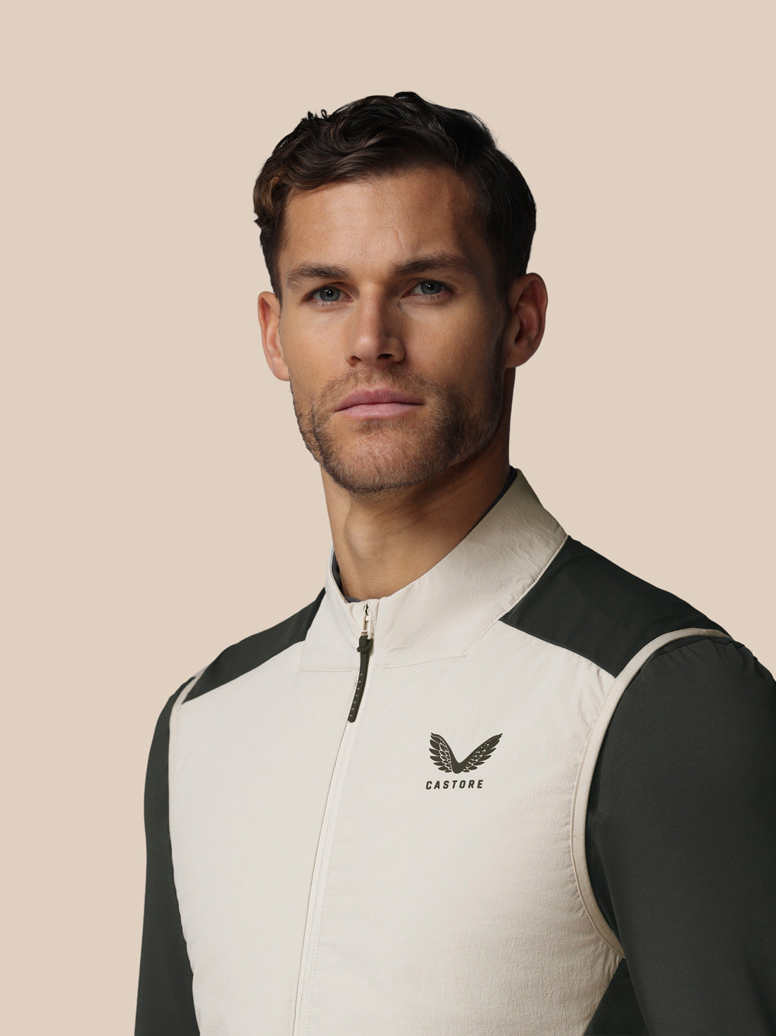 Man wearing a black and white jacket with a visible brand logo on a beige background