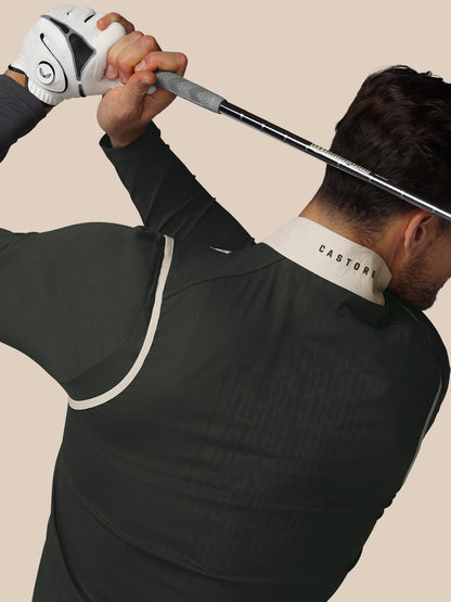Person in black athletic outfit with 'Castore' branding holding a golf club against a beige background