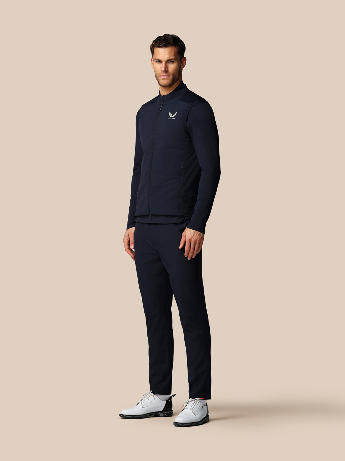 Man wearing a navy tracksuit with a logo on a beige background