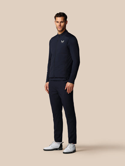 Man wearing a navy tracksuit with a logo on a beige background