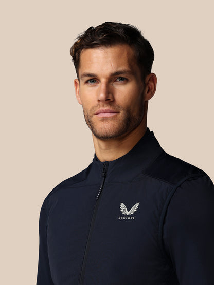 Man wearing a dark blue jacket with a logo on a beige background