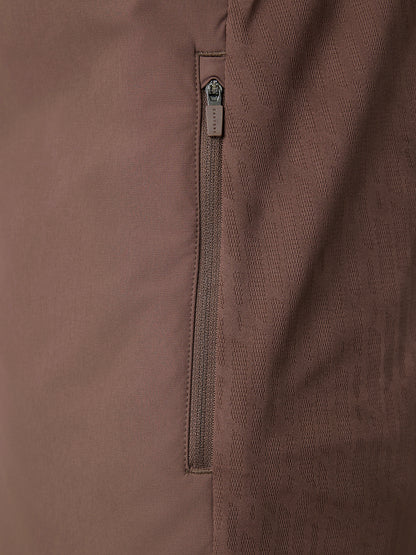Close-up of a brown fabric jacket showing a vertical zippered pocket with a silver zipper pull.