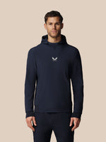 Man wearing a navy hoodie with a logo on a beige background