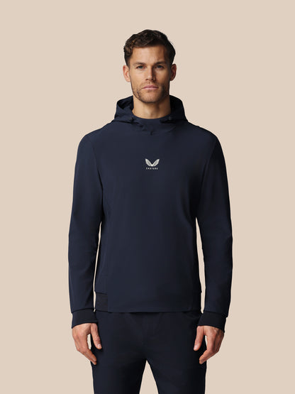 Man wearing a navy hoodie with a logo on a beige background