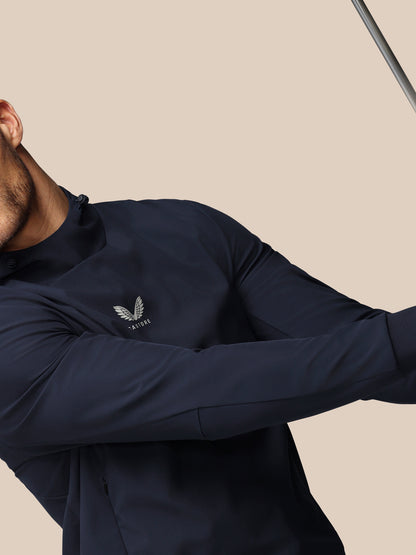 Person wearing a navy long-sleeve shirt with a logo on a beige background