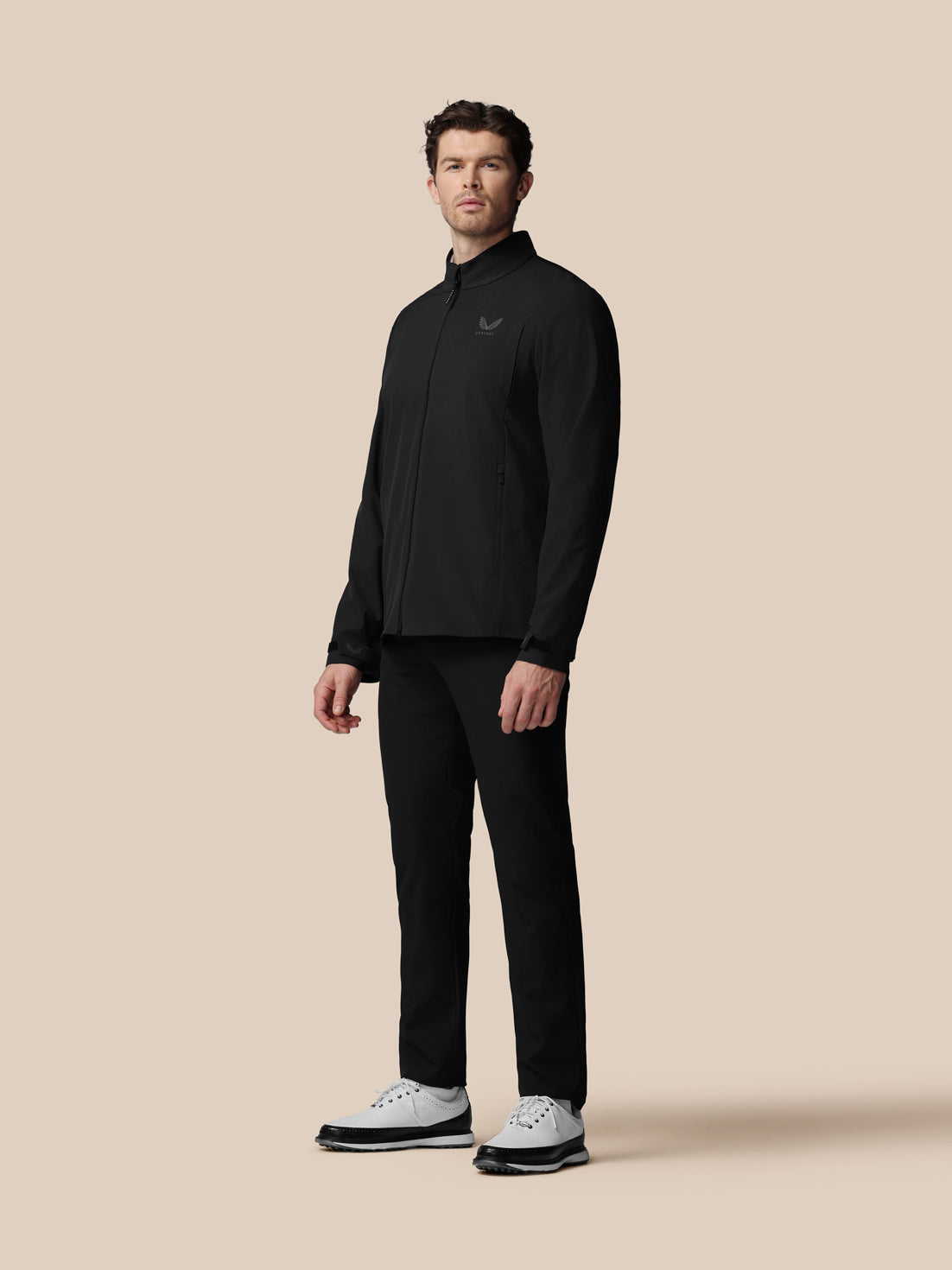 Man wearing a black outfit with a logo on a beige background