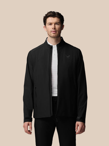 Man wearing a black jacket with a brand logo on a beige background