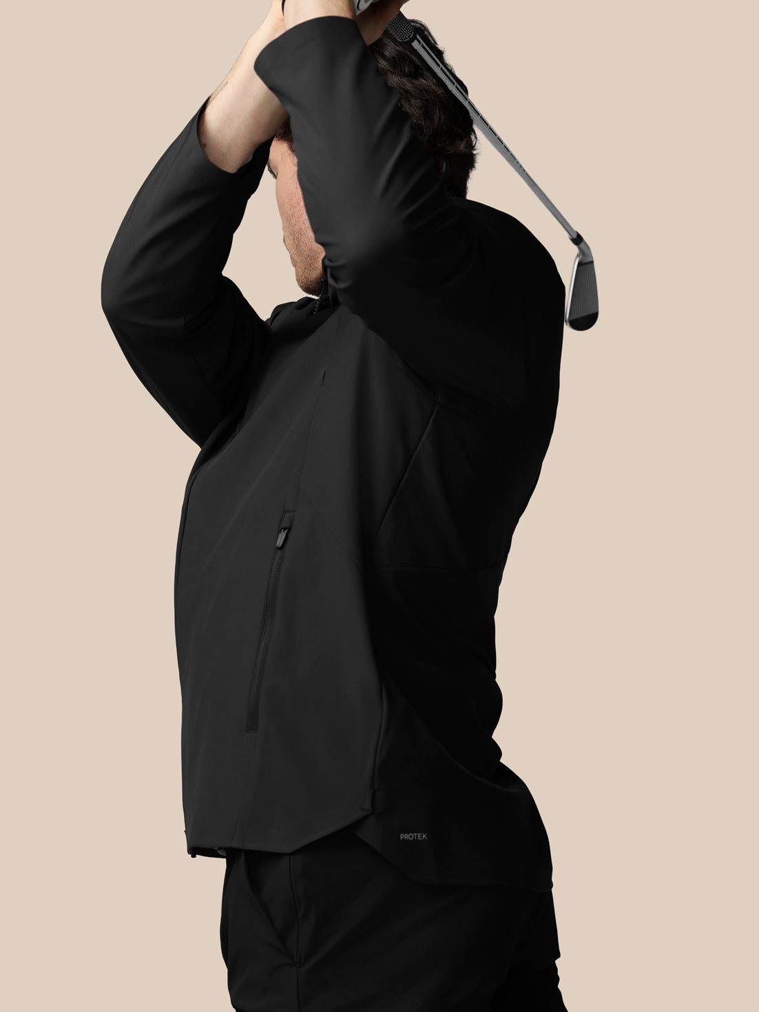 Person wearing a black jacket with a beige background