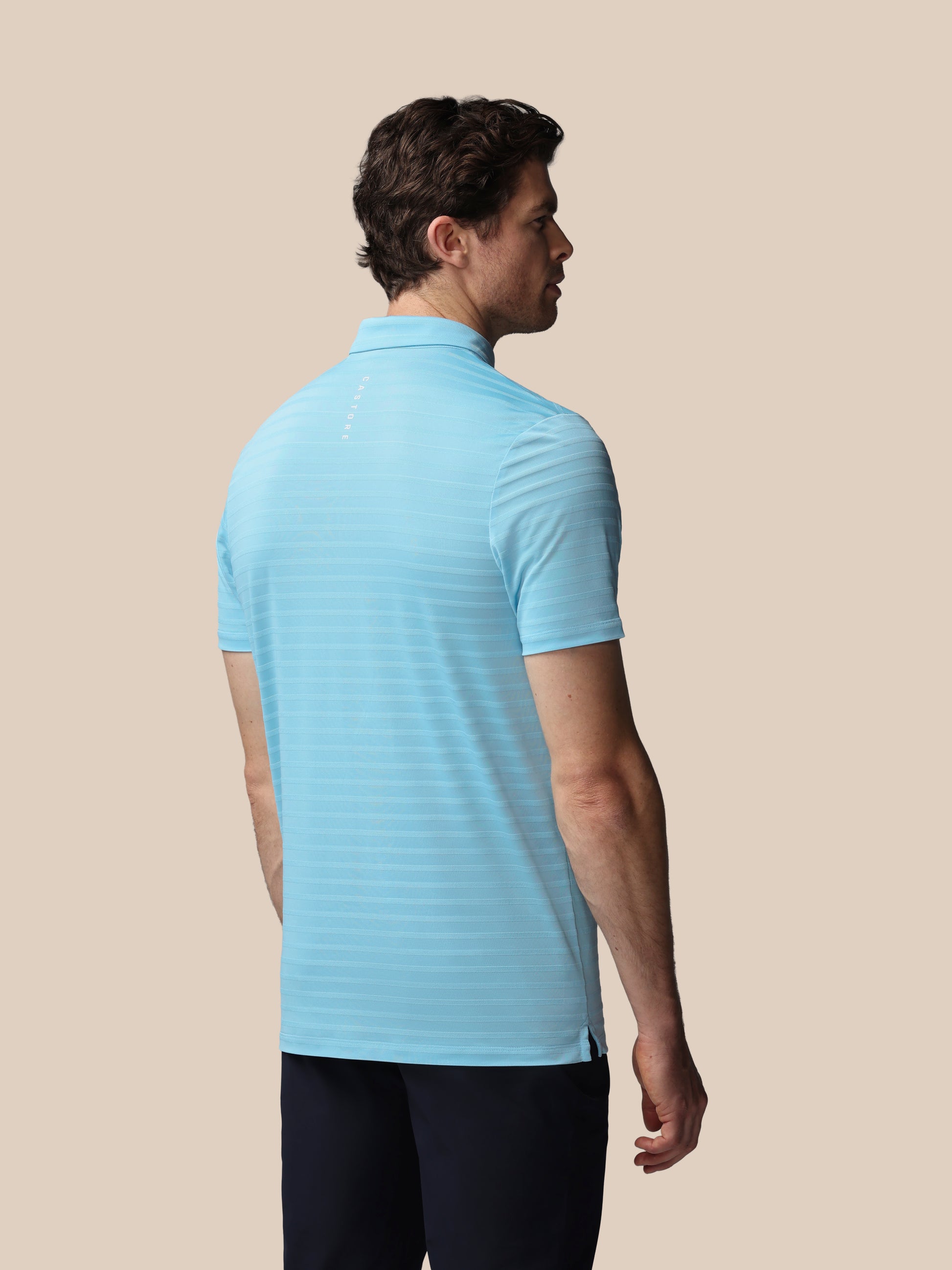 Man wearing a light blue striped polo shirt on a beige background