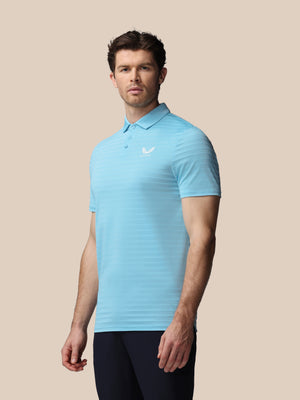 Man wearing a light blue polo shirt with a logo on a beige background