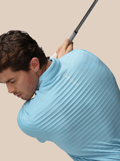Man in a light blue shirt holding a golf club against a beige background