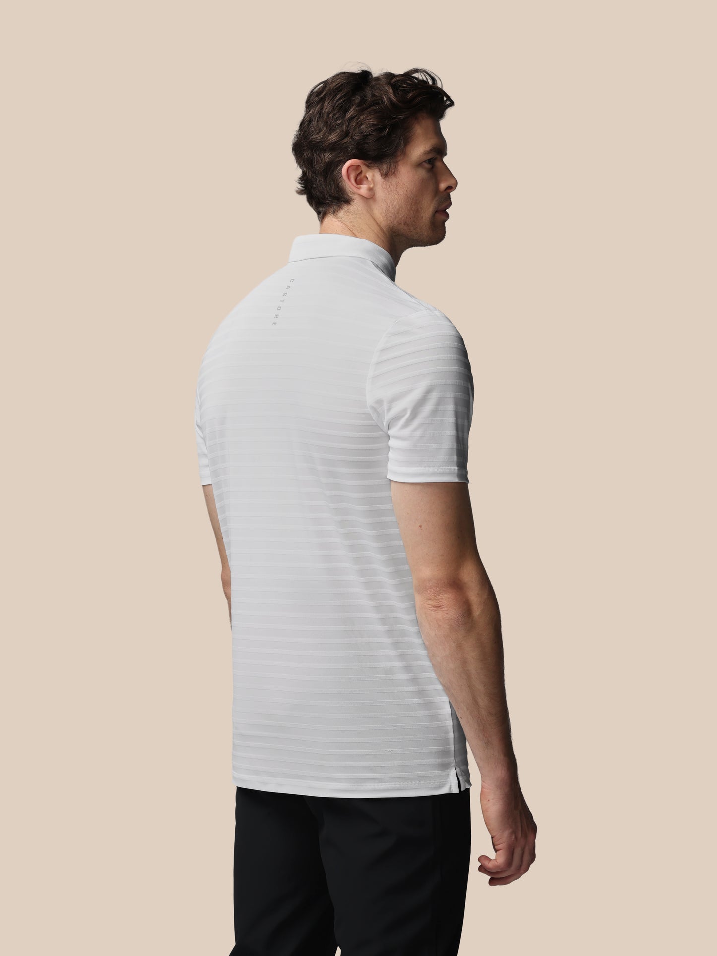 Man wearing a white striped polo shirt against a beige background