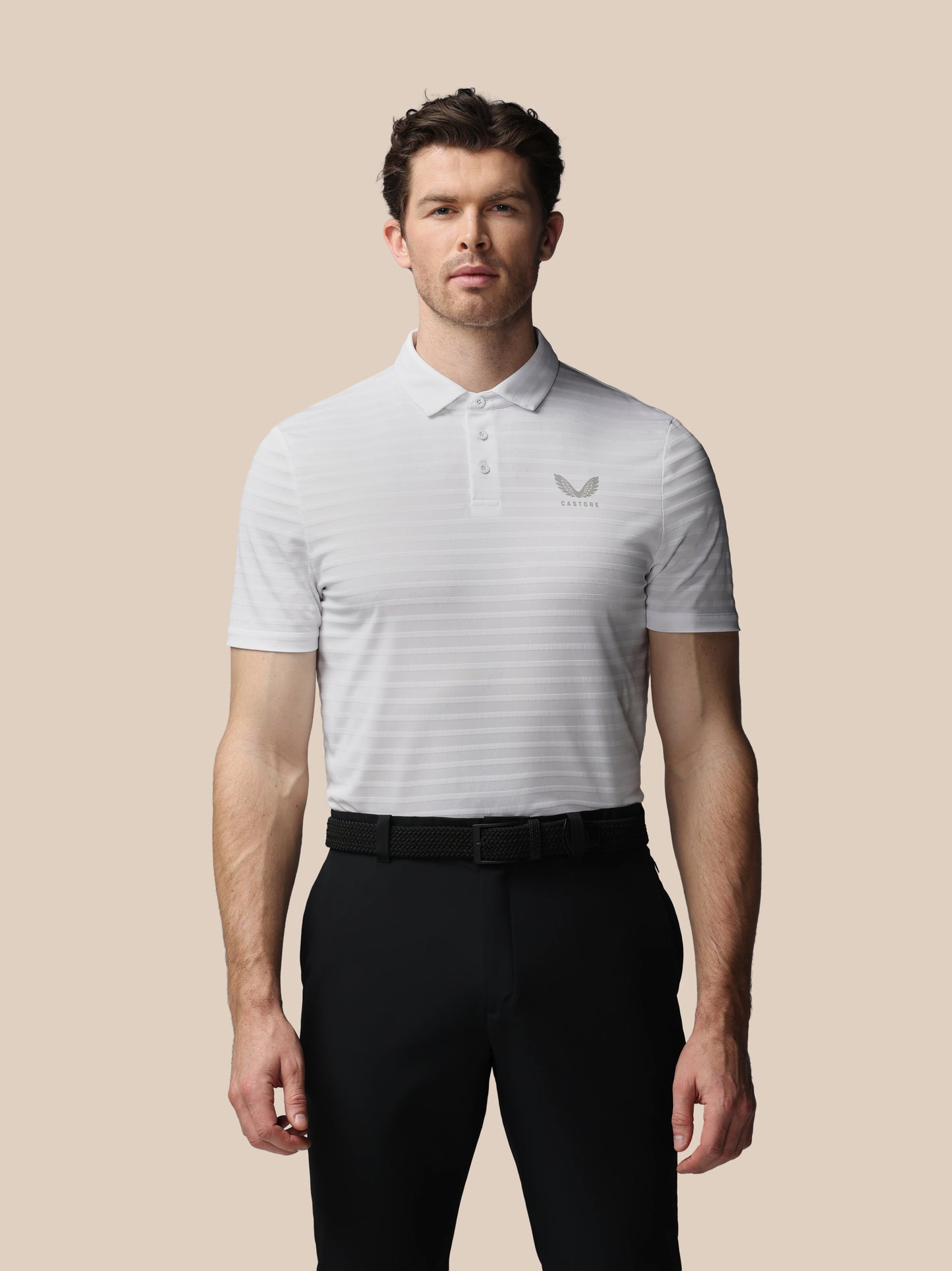 Man wearing a white striped polo shirt with a logo on a beige background