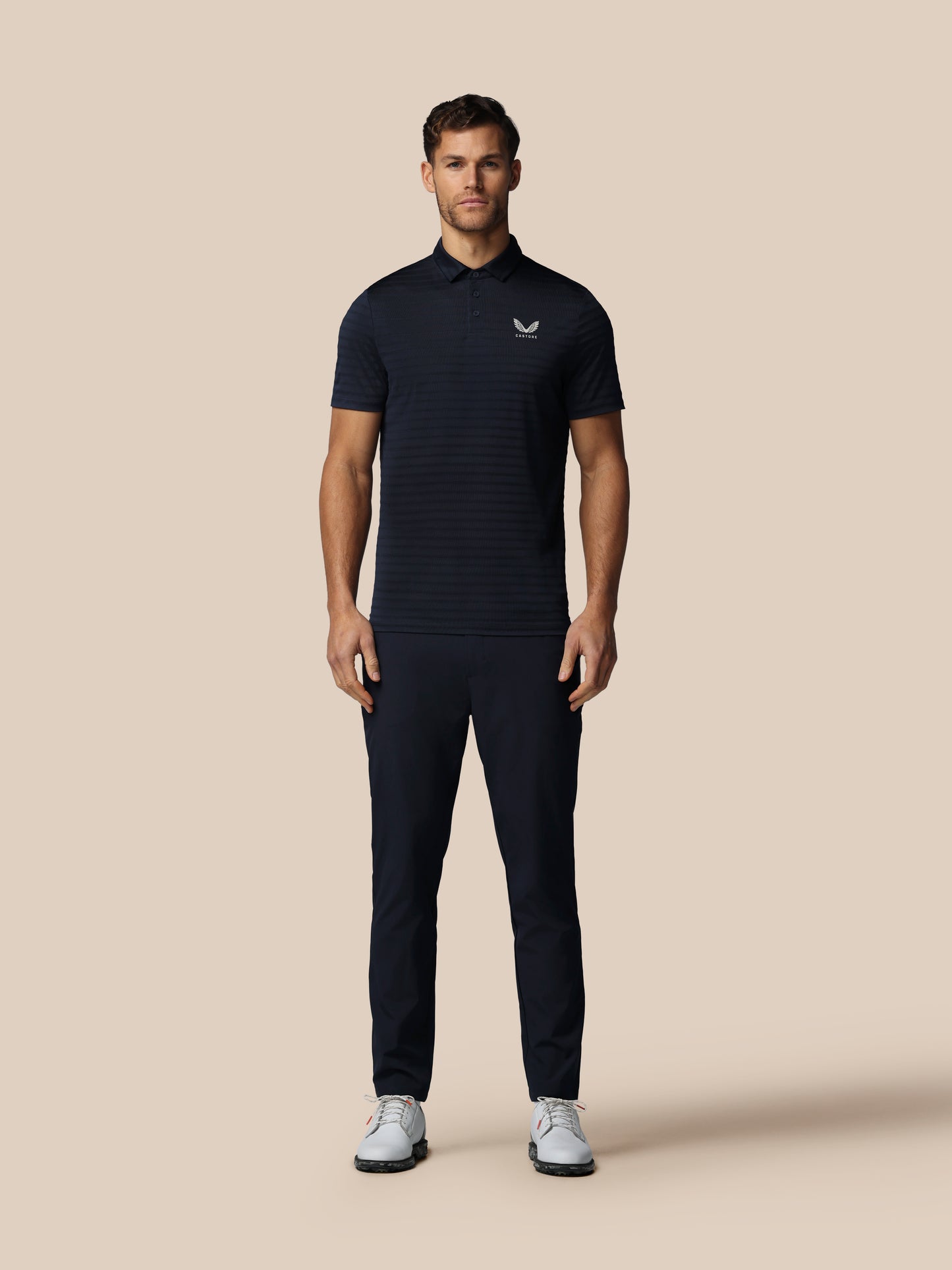 Man wearing a dark polo shirt and pants on a beige background