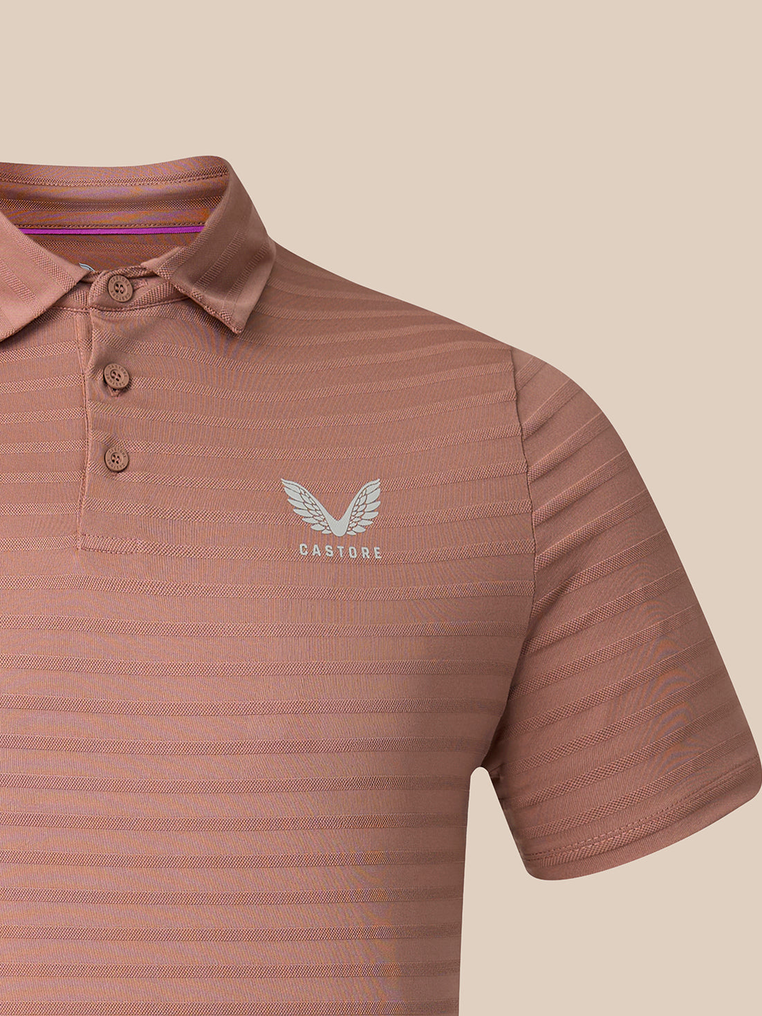 A close-up of a short-sleeve polo shirt in a dusty rose or mauve color with fine horizontal stripes, featuring a white embroidered wing logo and the brand name 'CASTORE' on the left chest.