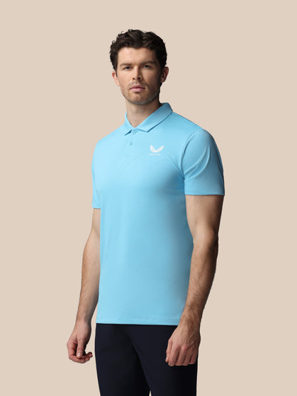 Man wearing a light blue polo shirt with a Castore logo on a beige background