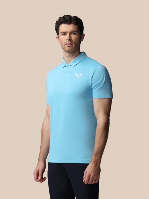Man wearing a light blue polo shirt with a Castore logo on a beige background