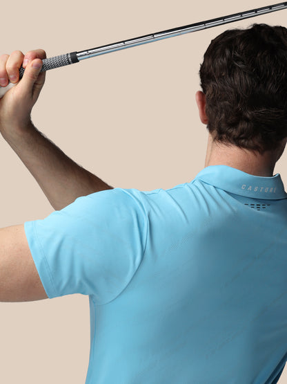 Person in a light blue shirt holding a golf club against a beige background