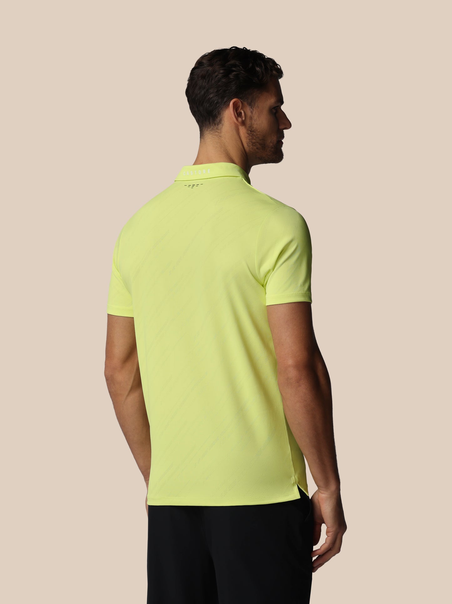 Man wearing a bright yellow polo shirt on a beige background