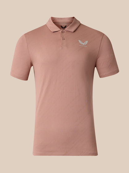 A short-sleeve polo shirt in a dusty rose pink color, featuring a small light gray wing logo on the left chest with the brand name 'Castore' underneath, displayed on a solid beige background.