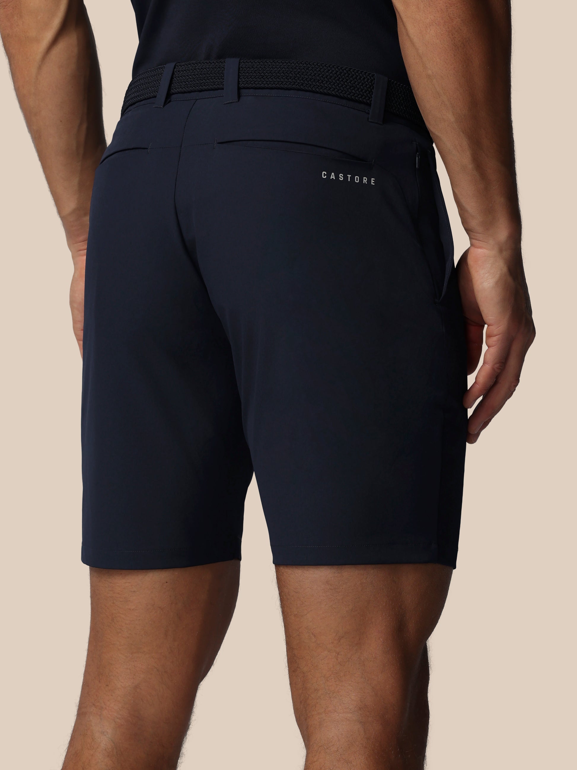 Navy shorts with a Castore brand logo on the back pocket against a beige background