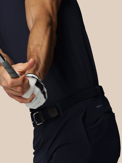 Person wearing a black outfit with a belt, holding a golf club.