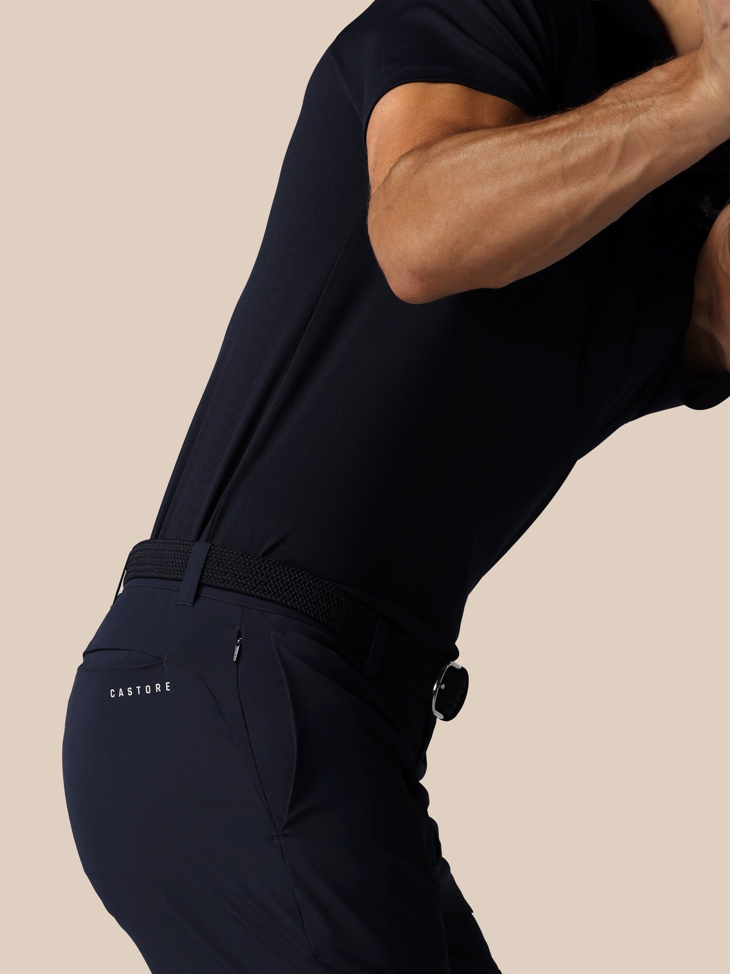 Person wearing a black outfit with 'Castore' branding on a beige background