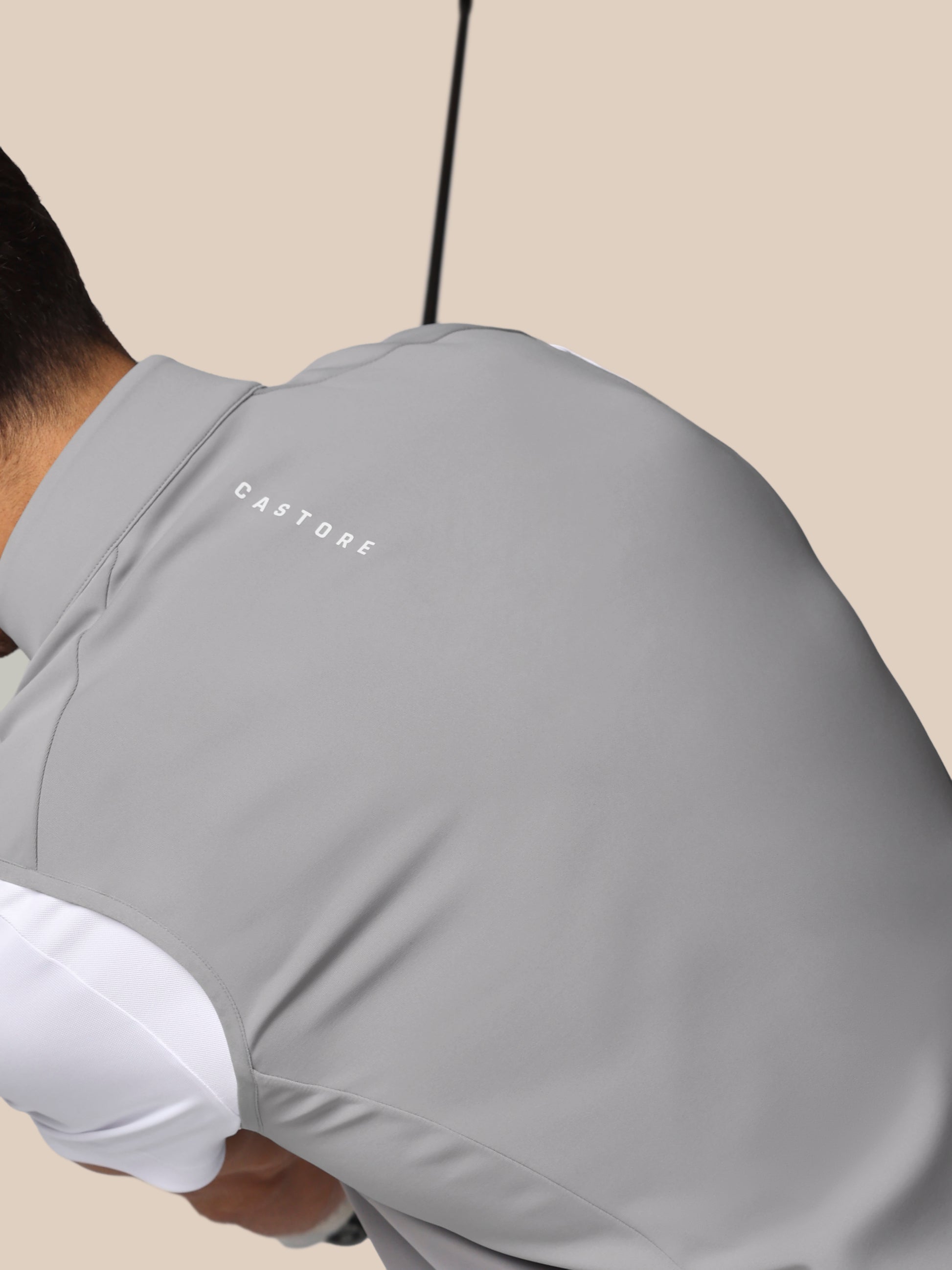Person wearing a gray hoodie with 'CASTORE' branding on a beige background