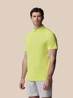 Man wearing a bright yellow polo shirt and white shorts on a beige background