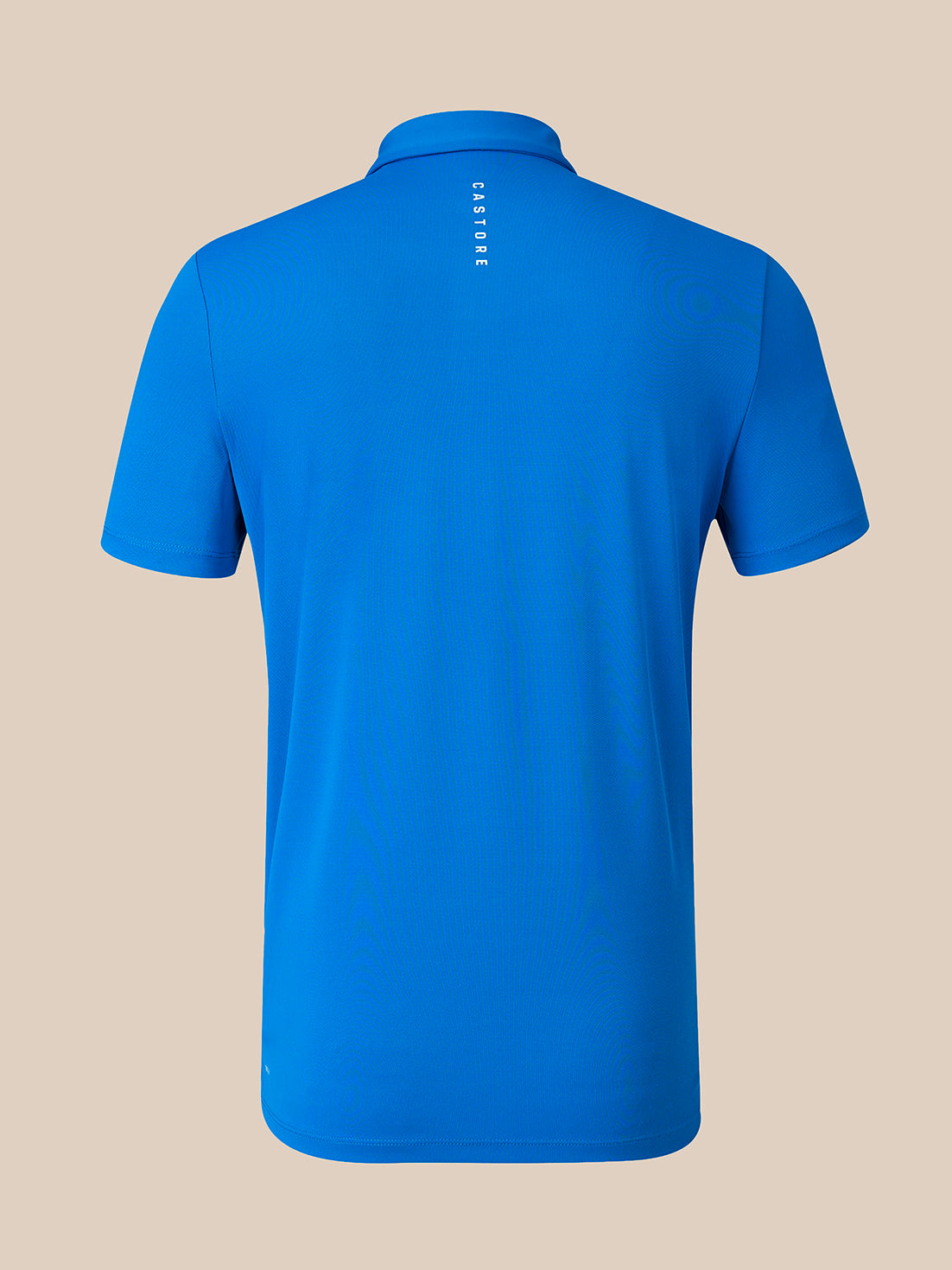 A bright blue short-sleeve polo shirt shown from the back, featuring a small vertical white 'CASTORE' logo on the upper back, set against a solid beige background.
