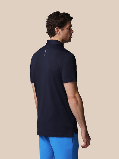 Man wearing a navy polo shirt with a beige background