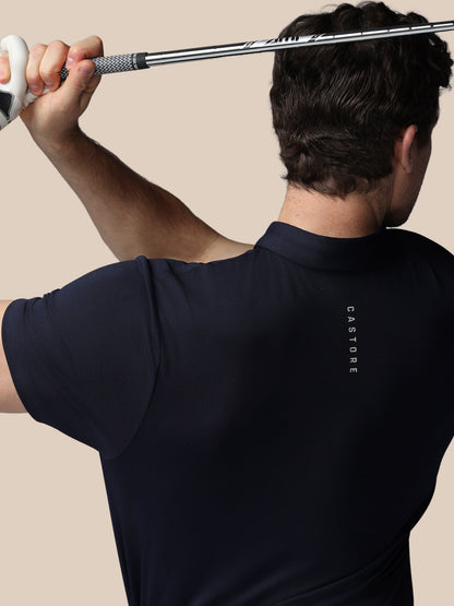 Person wearing a navy blue polo shirt with 'Castore' branding, holding a golf club.