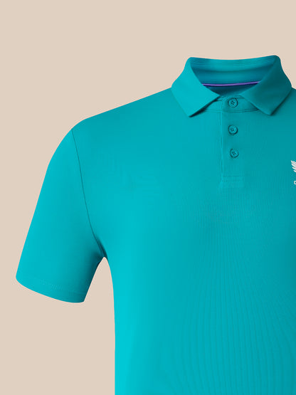 A close-up of a short-sleeve polo shirt in a bright turquoise color, featuring a three-button placket and a small white embroidered logo on the left chest, set against a solid beige background.