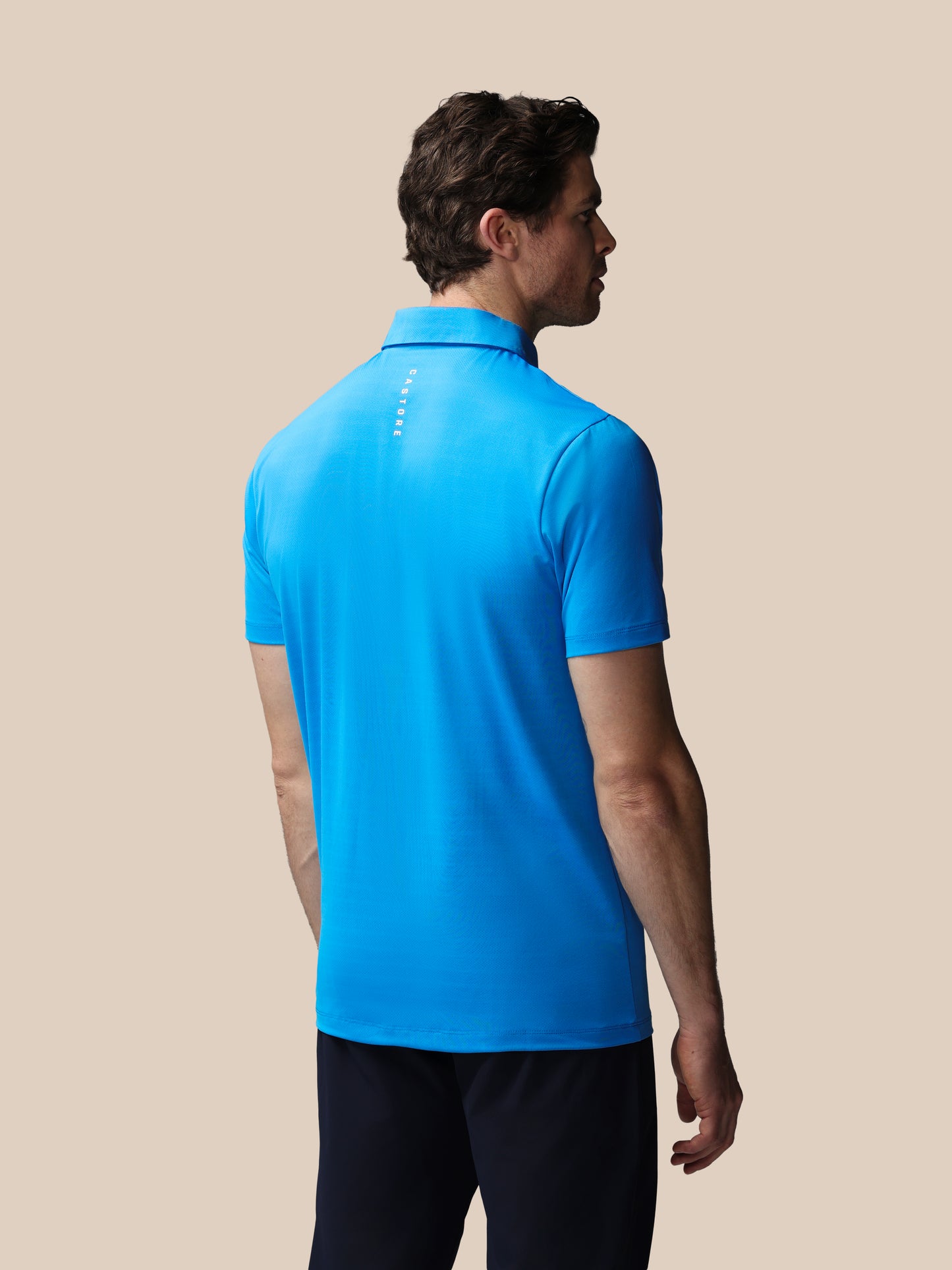 Man wearing a blue polo shirt on a beige background