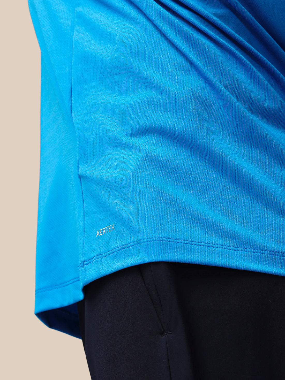 Close-up of a blue Castore shirt with a brand logo on a beige background