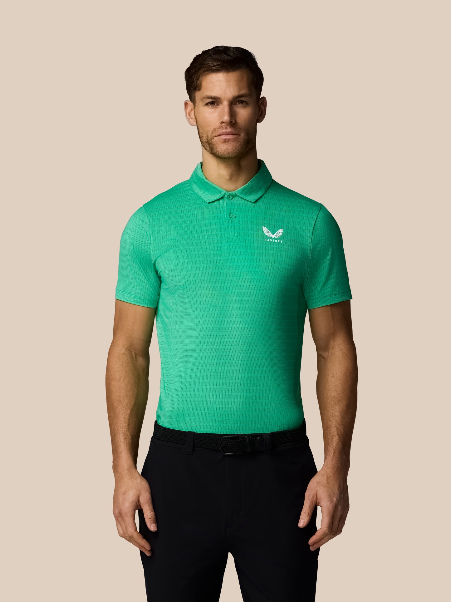 Man wearing a green striped polo shirt with Castore logo on a beige background